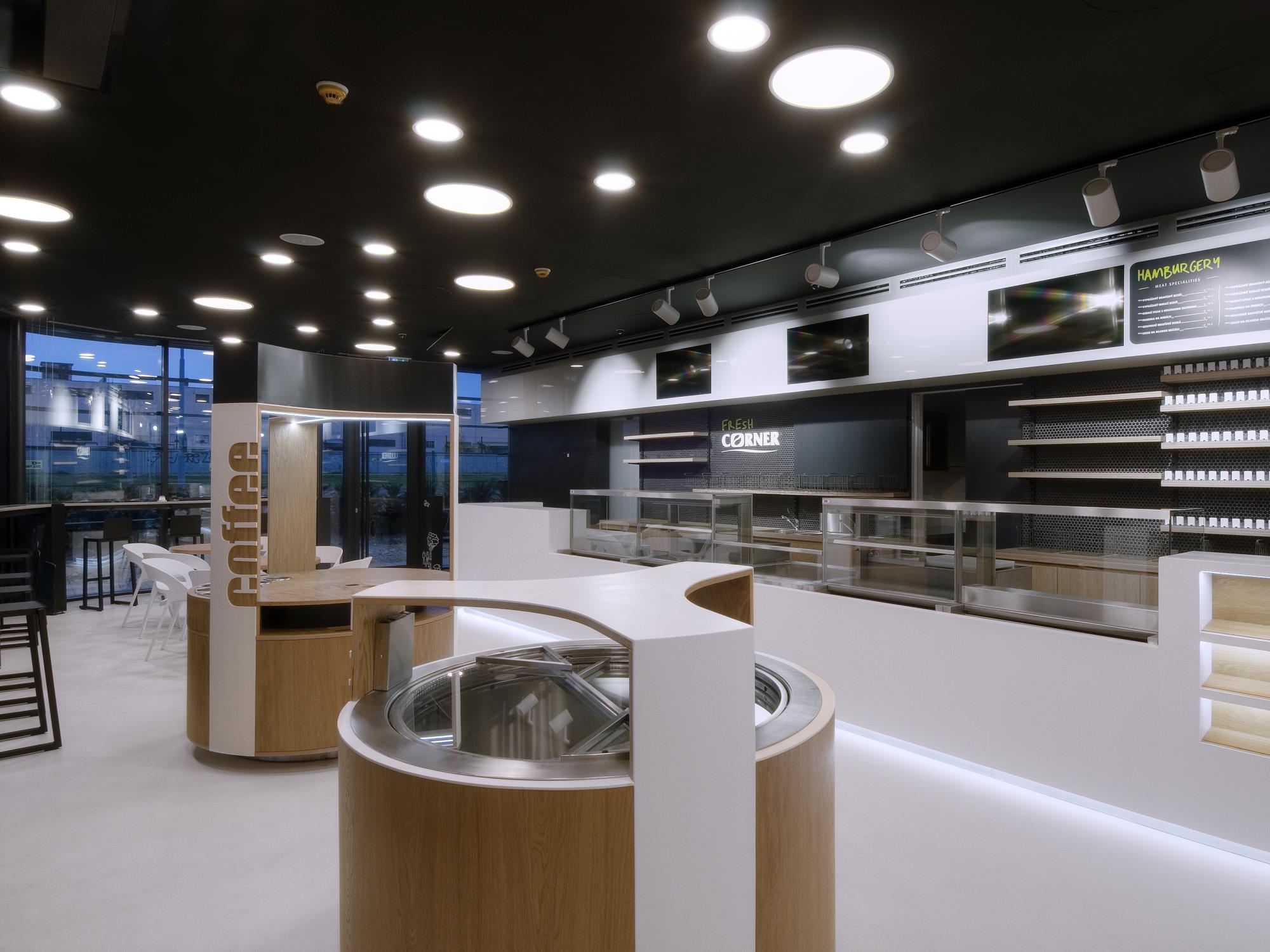 Kiosk, v ktorom sú zákazníci obslúžení s drevenými stolmi a bielym obkladom