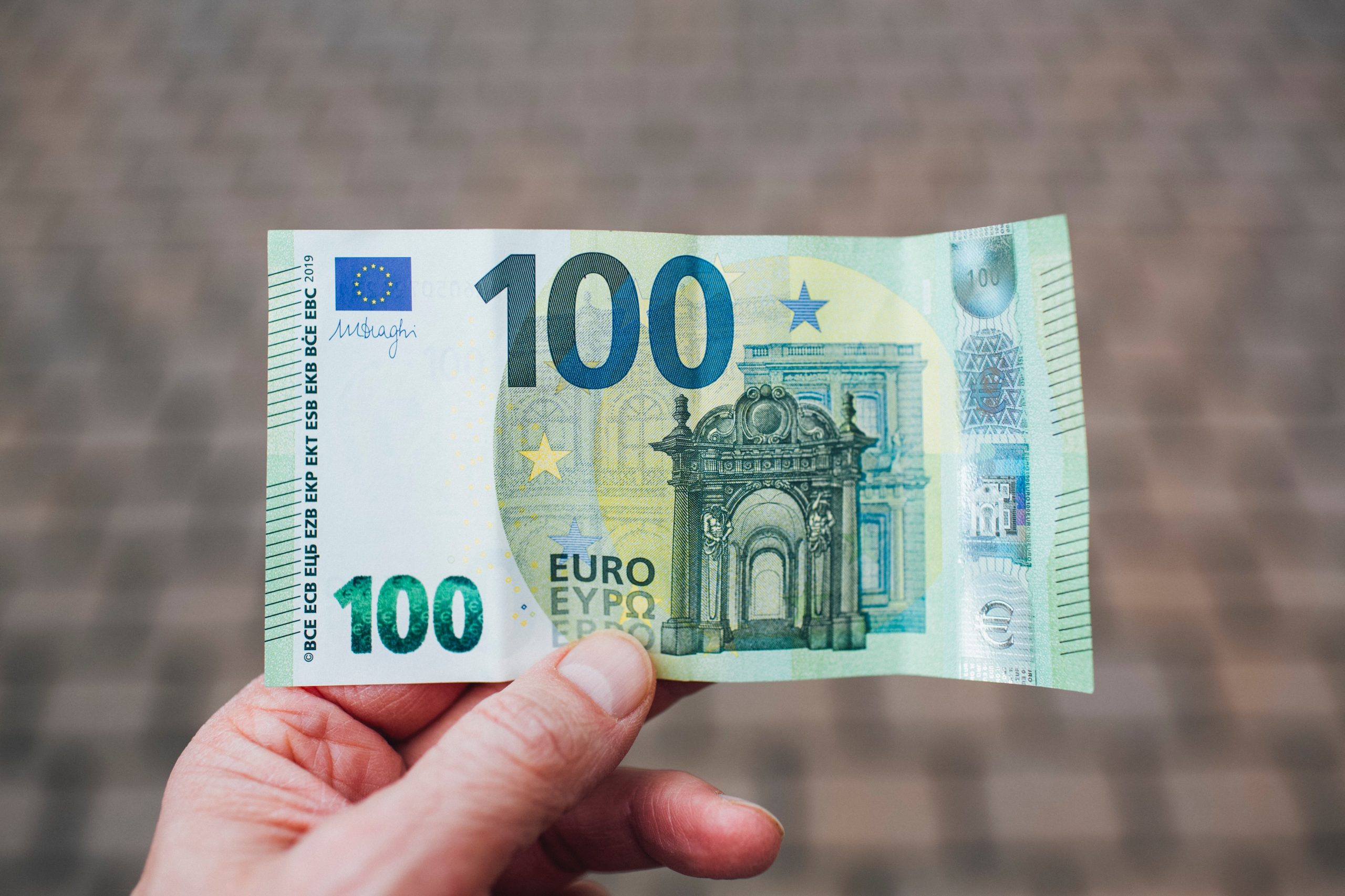muž držiaci stoeurovú bankovku