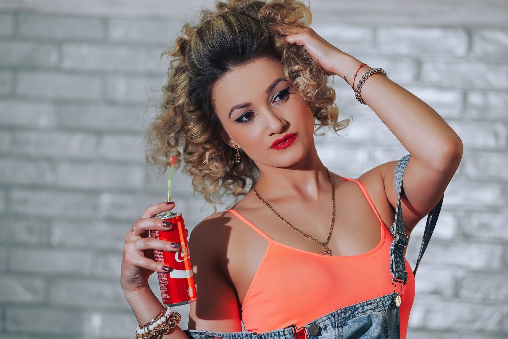 mladá krásna žena s plechovkou coca-coly