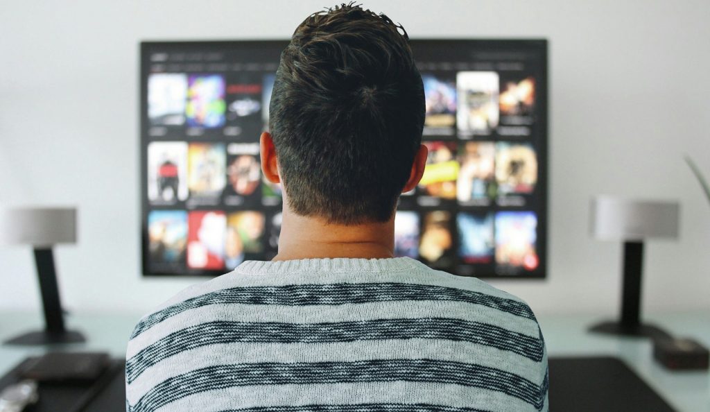 mladý muž sediaci pred televíznou obrazovkou a sledujúci seriál ABSTRACT na Netflixe